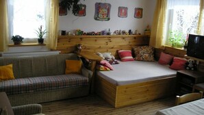 A cozy room with a sofa, a bed, a wooden headboard, and a TV.