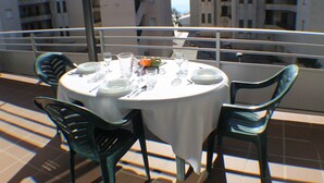 A round table with a white tablecloth, two green chairs, and a set of cutlery and plates.