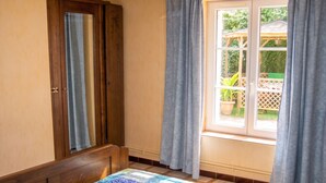Un dormitorio con cama, ventana con cortinas, puerta de madera y vista al exterior.