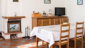 Una habitación con chimenea, televisión, mesa de comedor con sillas y obras de arte en las paredes.