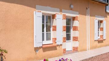 A building with a stucco exterior, white window shutters, and a brick base.