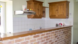 Una cocina con isla de ladrillo, armarios de madera y salpicadero de azulejos blancos.