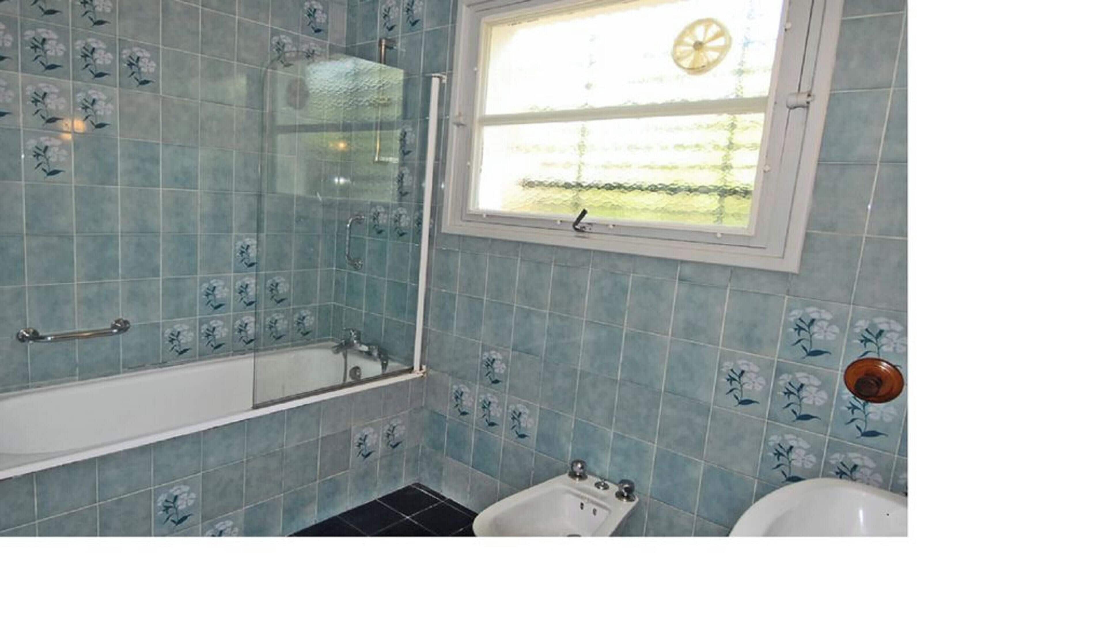 A bathroom with a bathtub, a window, and a toilet.