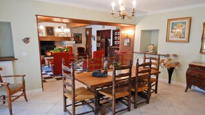 A dining area with a wooden table and chairs, a chandelier, and a red chair in the background. - Homerez - House in Lannes, terrace & garden (Lannes)