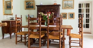 A dining room with a wooden table, chairs, and a vase of flowers. - Homerez - House in Lannes, terrace & garden (Lannes)