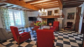 A living room with a checkered floor, red armchairs, a fireplace, and a television.