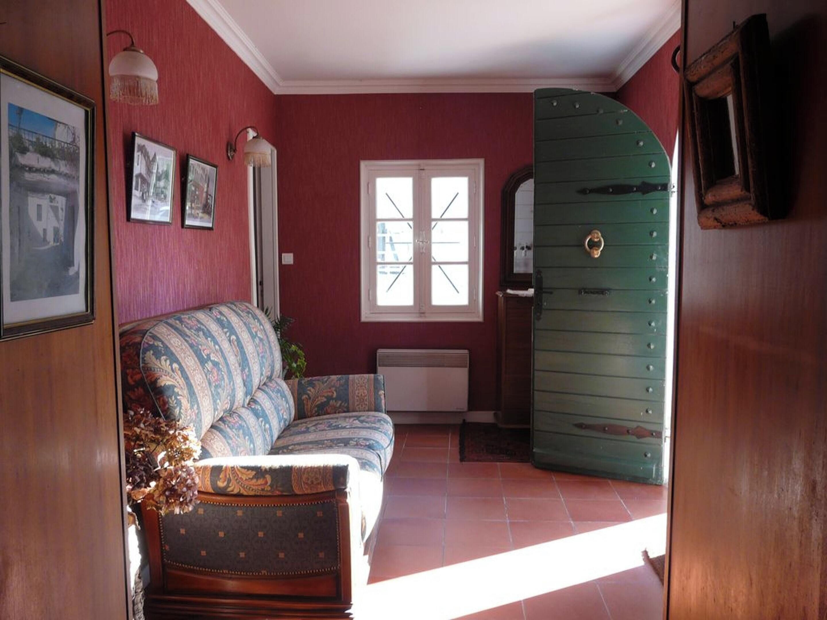 Une pièce avec un canapé à motifs, une commode verte et un radiateur.