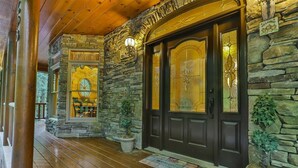 A stone exterior with a dark wooden door, a welcome mat, and a potted plant.