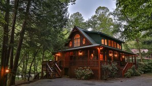 A cabin with a porch, wooden exterior, and multiple windows.