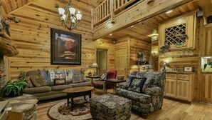 A log cabin interior with a living room, dining area, and kitchen.