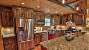 Eine Küche mit Holzausstattung, einem Edelstahl-Kühlschrank, Granit-Arbeitsplatten und einem eingebauten Backofen.