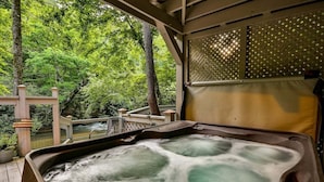 A hot tub with a view of a wooden deck and trees. - Rendezvous on the River | Ellijay, GA (Ellijay)