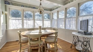 A dining area with a round table, chairs, and a television on a side table.