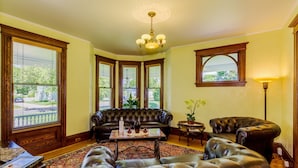 A living room with a leather sofa, a round coffee table, and a chandelier.