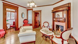 A spacious living room with a fireplace, wooden furniture, and a chandelier.