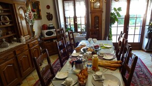 A dining room with a large table set for a meal, surrounded by wooden chairs. - Aux Orangers (Luxe)