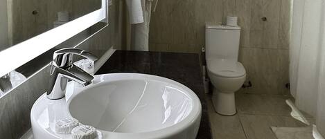 Un baño moderno con un lavabo grande de color blanco, inodoro y zona de ducha.