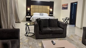 A hotel room with a bed, a sofa, a coffee table, and a TV. - Rollace Hotel Lagos INTL (Lagos)