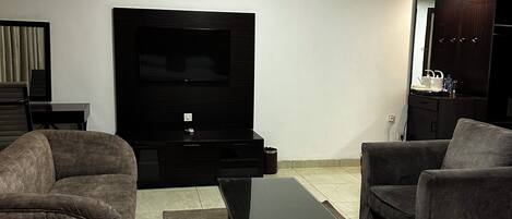 A modern hotel room with a flat-screen TV, a sofa, a coffee table, and a bed.