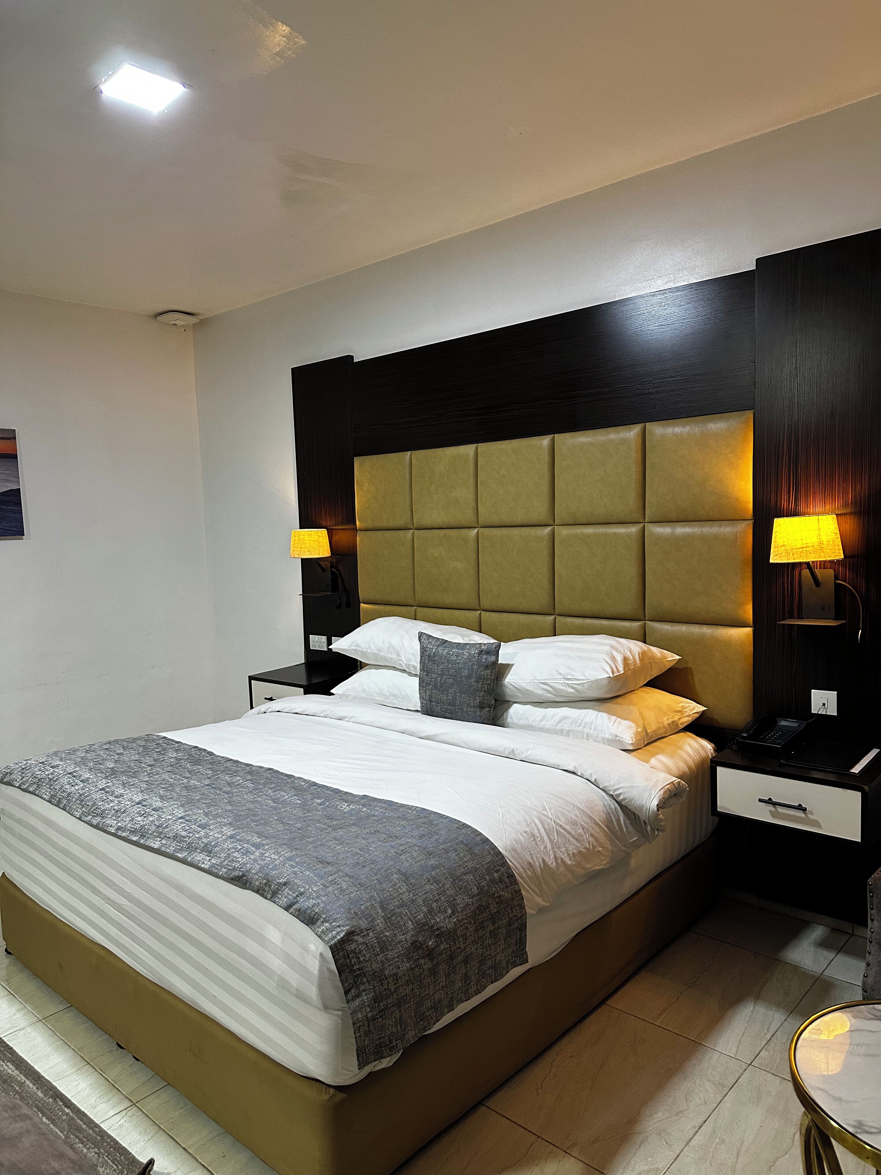 Une chambre d’hôtel moderne avec un grand lit, deux tables de chevet avec des lampes, une table d’appoint et une petite table ronde.