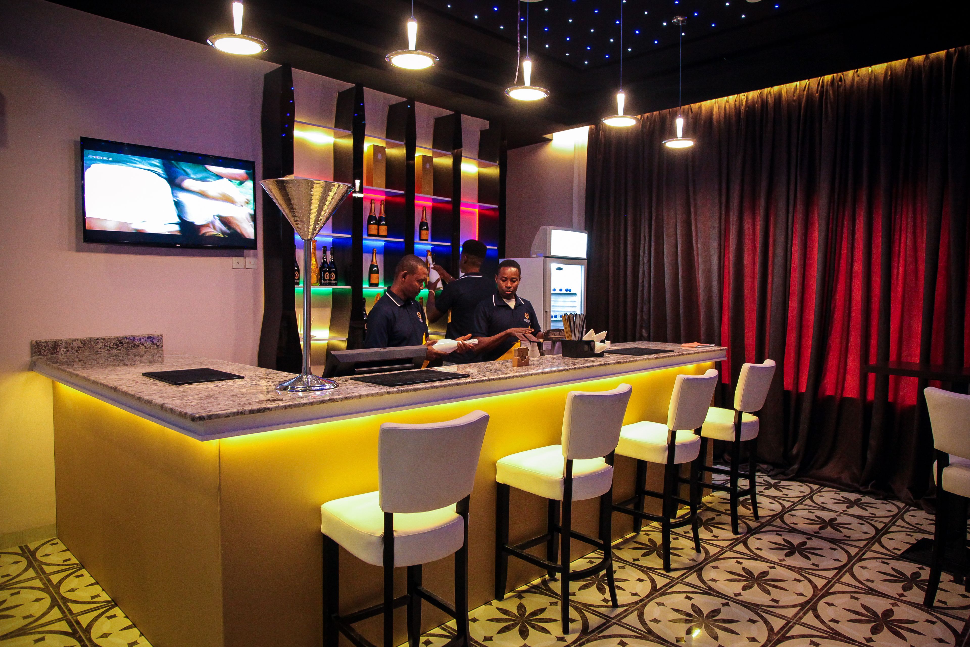 A bar area with a counter, bar stools, and a television screen.