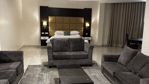 A modern living room with a sofa set, a coffee table, and a headboard with built-in lighting. - Rollace Hotel Lagos INTL (Lagos)