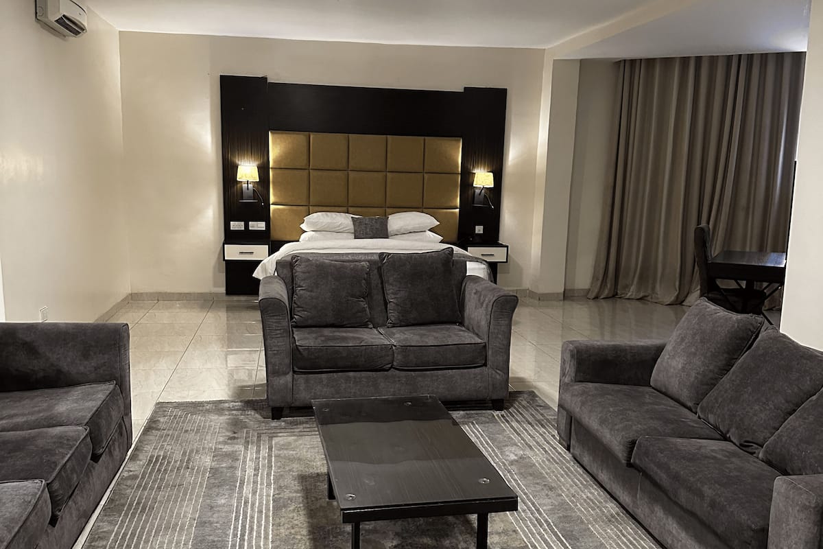 Una sala de estar moderna con un conjunto de sofás, una mesa de centro y un cabecero con iluminación integrada.