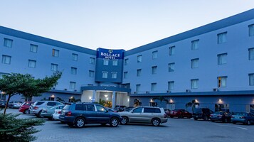 A hotel with a large sign reading "Rollace Hotel" and multiple parking spaces in front.