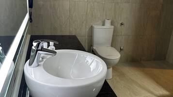 Un baño moderno con lavamanos blanco, encimera negra y un inodoro.