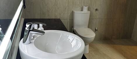 A modern bathroom with a white sink, black countertop, and a toilet.