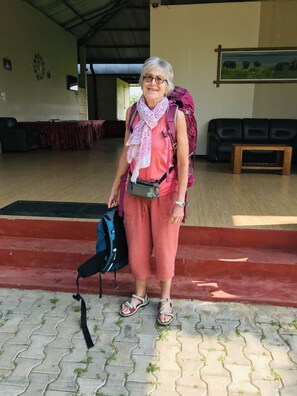 A person standing in a room with a red carpet, a black couch, and a wooden table. - Rivonway Hotel Polonnaruwa (Giritale)
