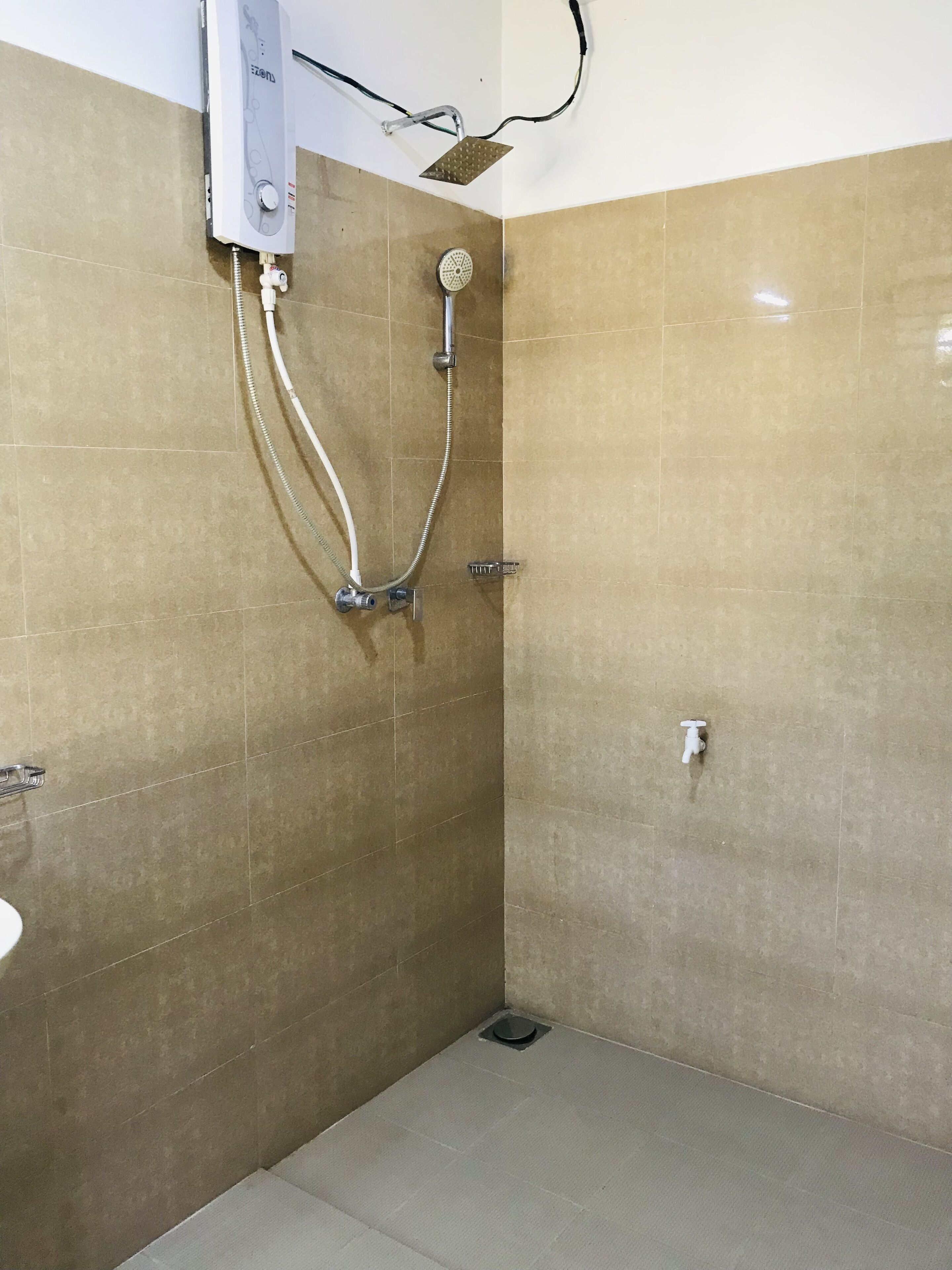 A small, tiled bathroom with a shower, a toilet, and a sink.