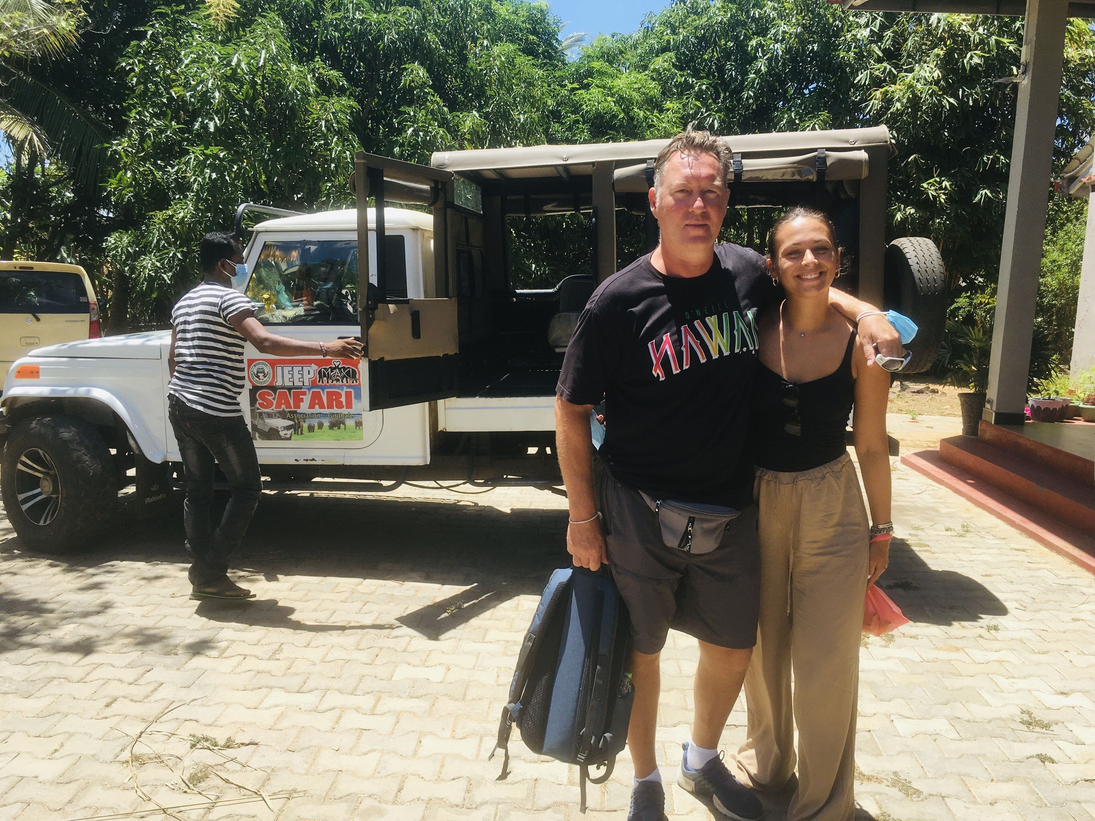 A man and woman standing in front of a safari vehicle with a sign that reads "JEEP MAXI SAFARI".