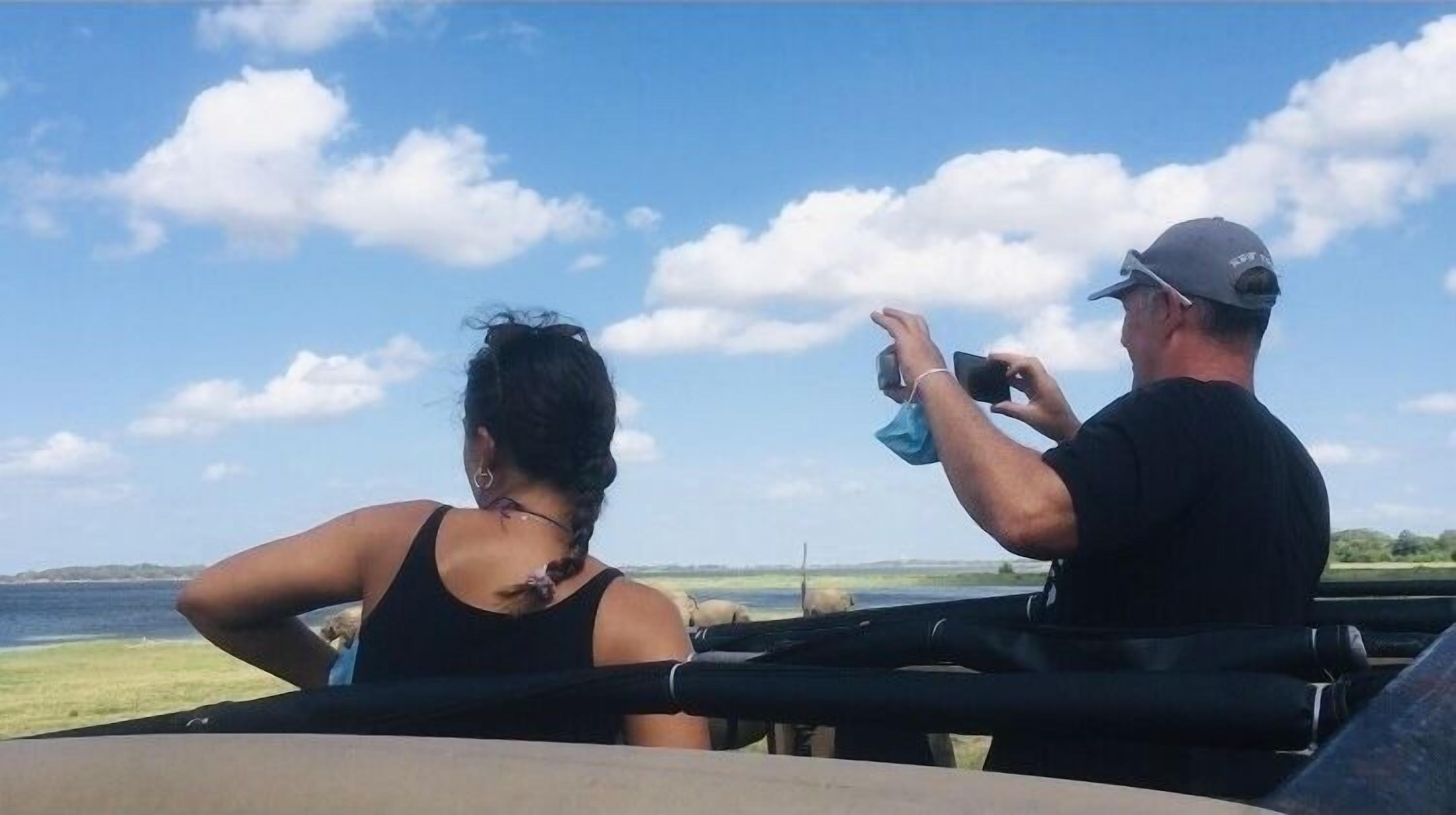 Two people on a boat with a view of the water and sky.