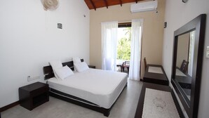 A bedroom with a bed, a nightstand, a TV, and a window with curtains. - Dreamvilla (Kochchikade)