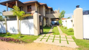 A two-story house with a covered patio, a paved driveway, and a well-maintained lawn. - Dreamvilla (Kochchikade)