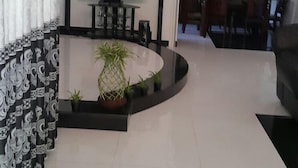 A modern living room with a curved black coffee table, a flat-screen TV, and a dining area in the background. - Dreamvilla (Kochchikade)