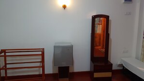 A room with a wooden chair, a small refrigerator, a mirror, and a bed. - Adannz view (Ella)