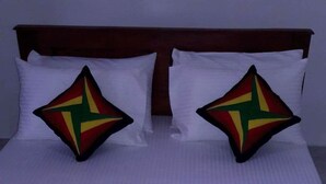 A neatly made bed with a striped bedspread and two pillows with a star design. - Adannz view (Ella)