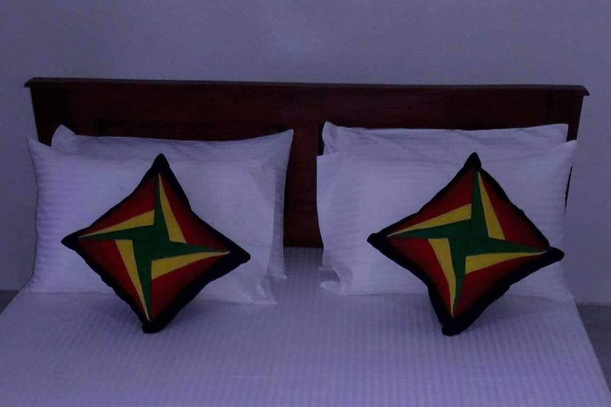A neatly made bed with a striped bedspread and two pillows with a star design.