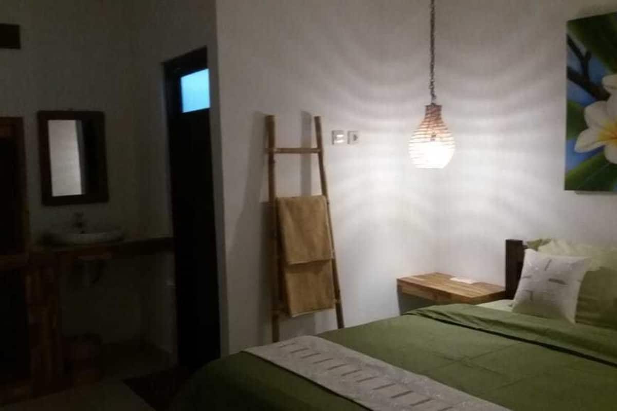A bedroom with a bed, a nightstand, a mirror, a wooden ladder, and a hanging light fixture.