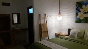 A bedroom with a bed, a nightstand, a mirror, a wooden ladder, and a hanging light fixture. - Cape Rose (Gili Trawangan)