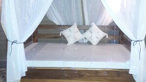 Ein Bett mit Holzrahmen, weißer Bettwäsche und einem Baldachin mit Lichterketten.