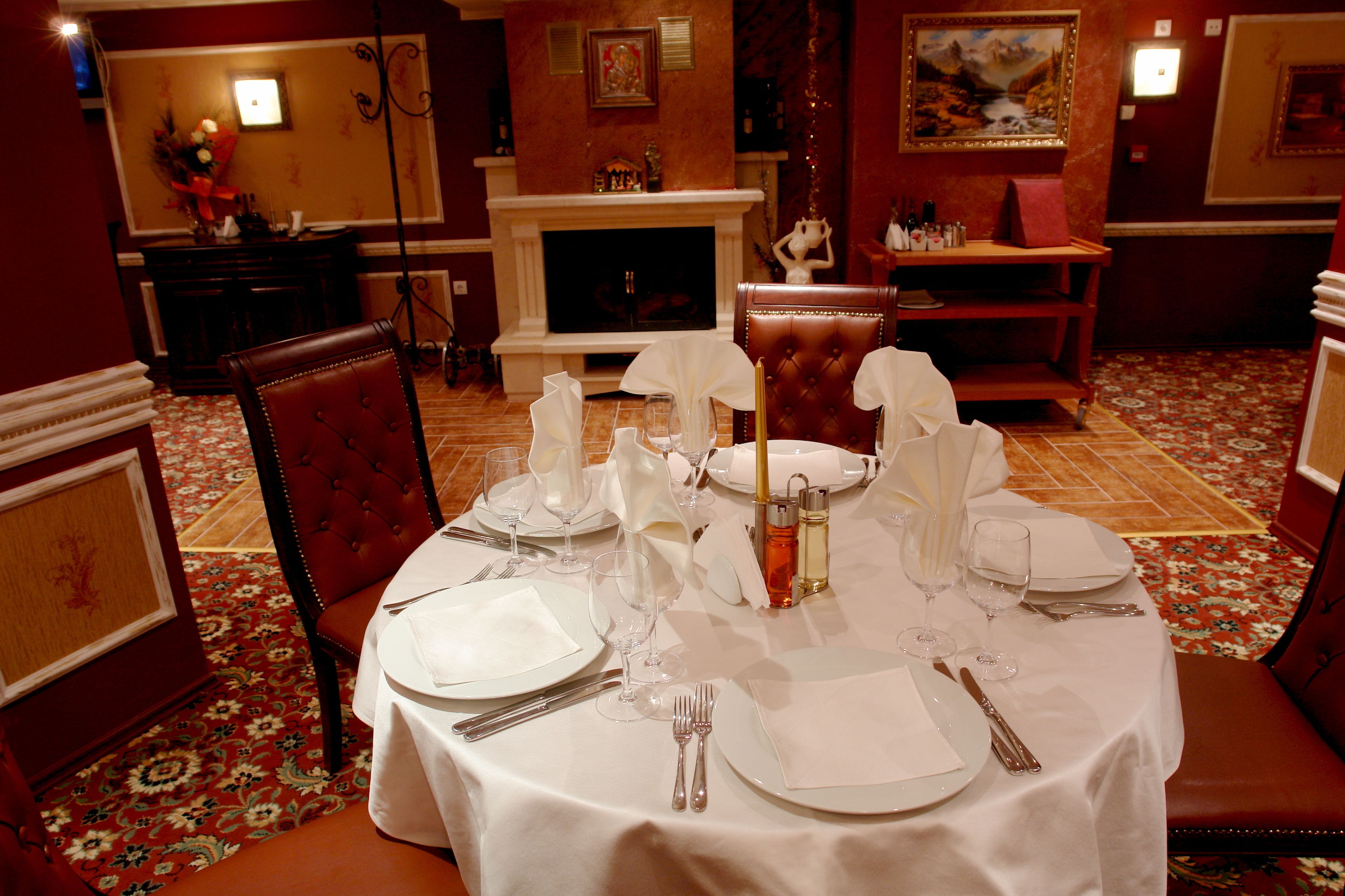 Mesa de comedor dispuesta para una comida formal, con manteles blancos, cubertería y cristalería.