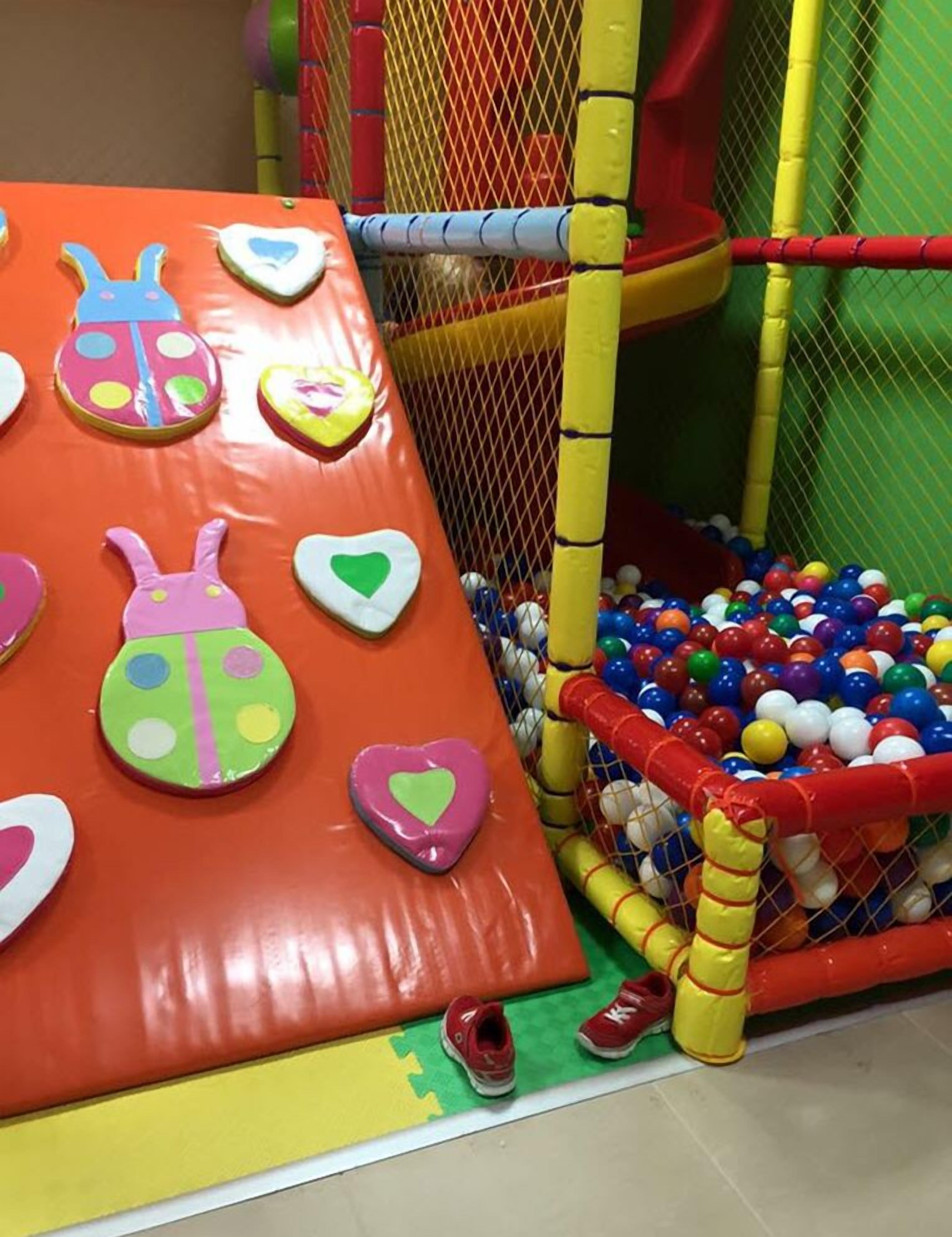 Un'area giochi per bambini con una piscina di palline e una parete di arrampicata decorata con cuori.