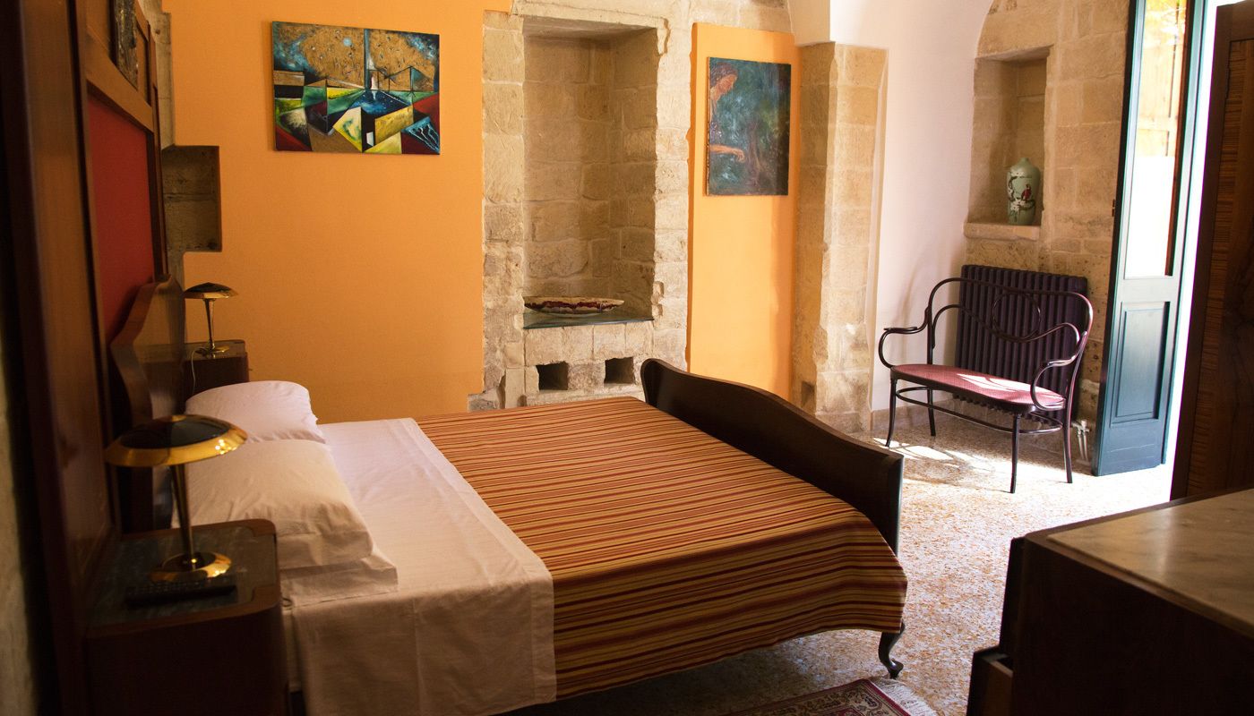 A bedroom with a bed, a chair, a nightstand, and a painting on the wall.
