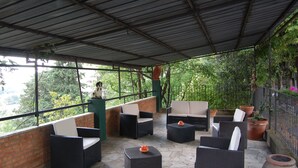 Un espacio de estar al aire libre cubierto con mobiliario de mimbre y plantas en macetas.