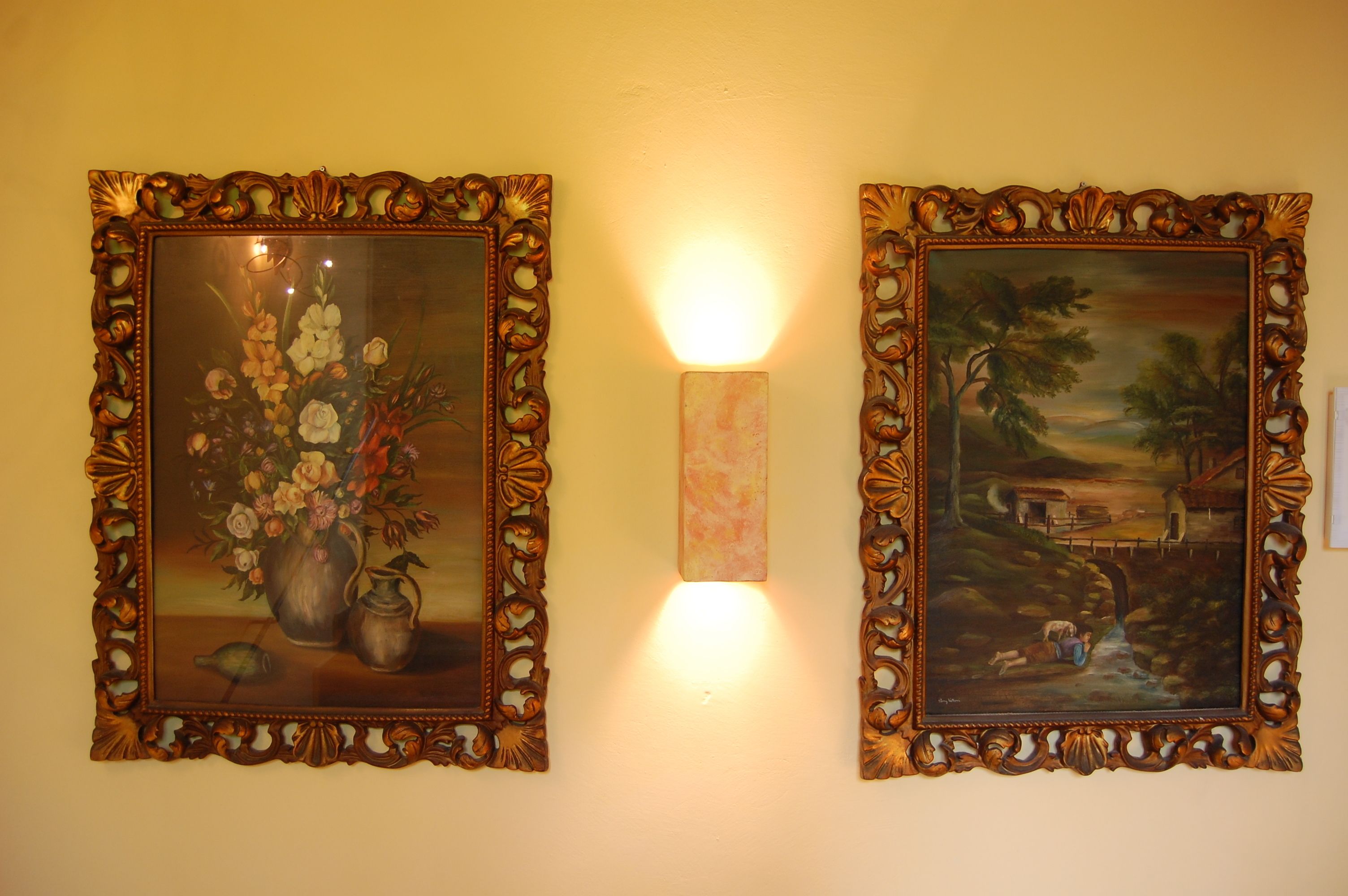 Deux tableaux richement décorés, avec un luminaire placé entre les deux.