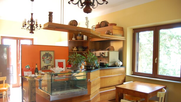Una cocina con armarios de madera, una vitrina de vidrio y una zona de comedor con una mesa y sillas.