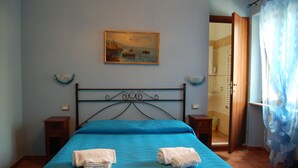 Un dormitorio con cama, un cuadro y la puerta de un baño.